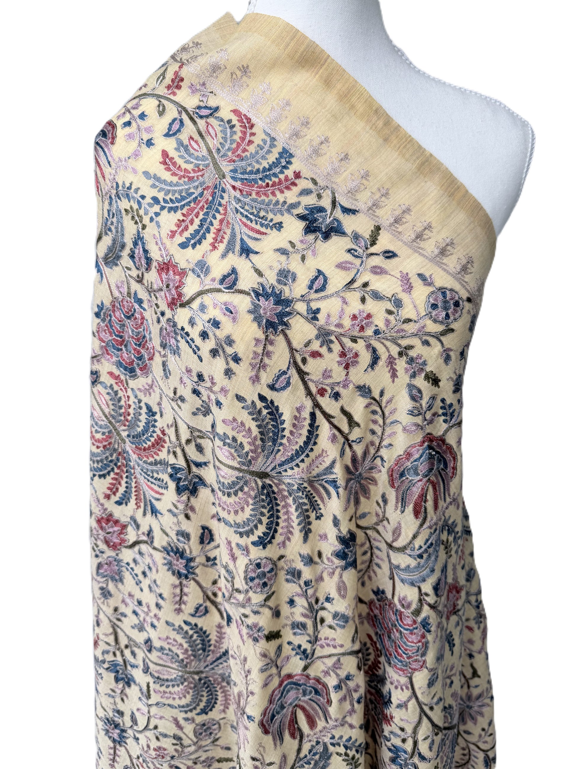 Beige fabric with floral embroidery on a mannequin against a white background